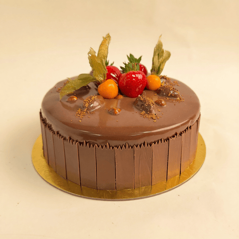 Luxury chocolate rocher cake covered in ganache and decorated with strawberries