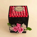 Box of pink and red chocolates with decorative flowers on a beige background